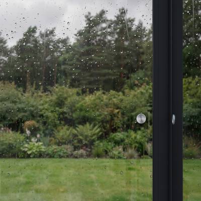 Blick durch eine Glasscheibe in den verregneten Garten 