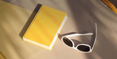 Sonnenliege mit einem gelben Buch und einer Sonnenbrille